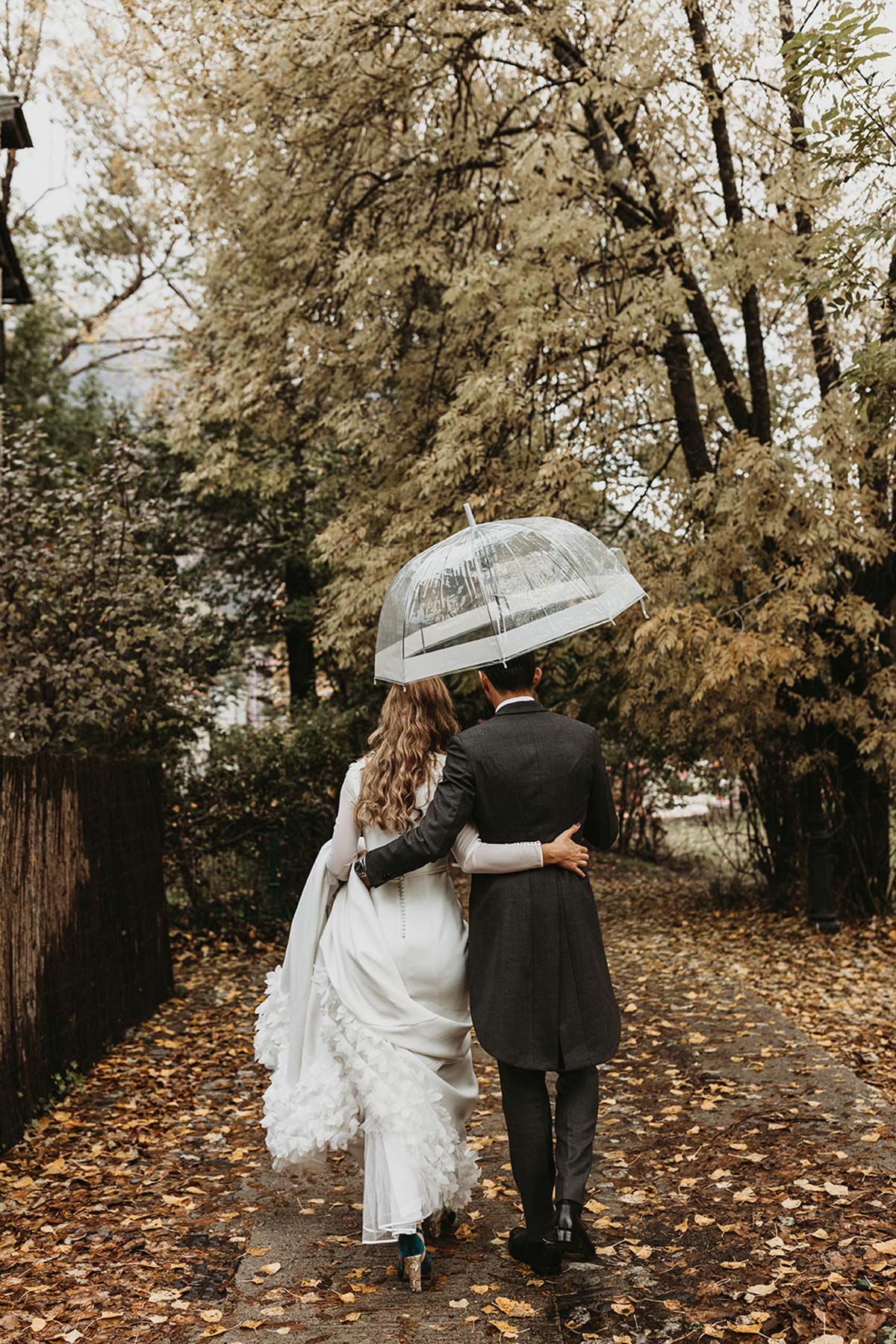 Fotografía de novios bajo la lluvia paraguas boda de invierno
